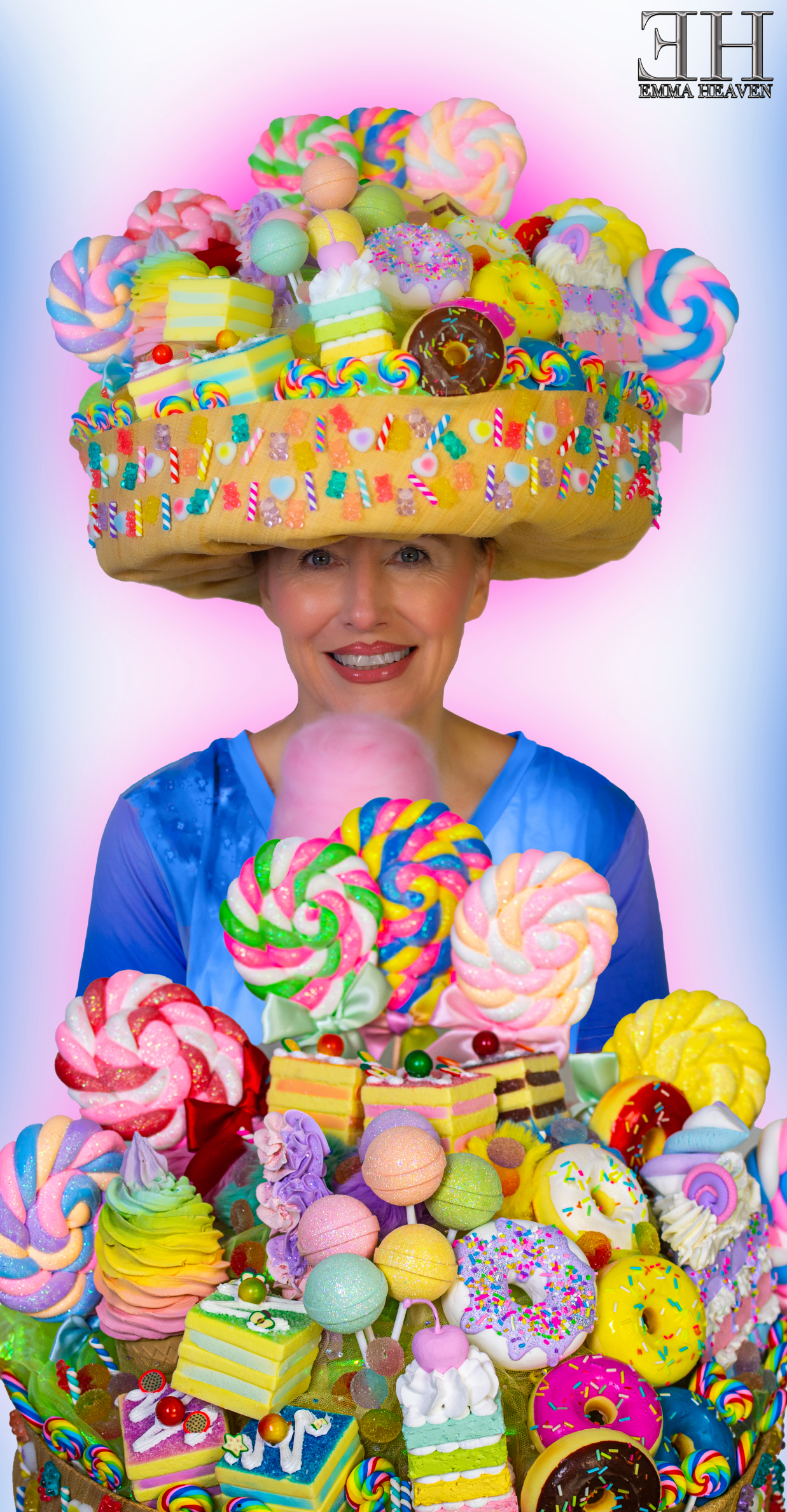 A woman wearing a large candy-themed hat filled with colorful sweets and desserts, smiling and holding more candy items, with a vibrant pink and blue background.